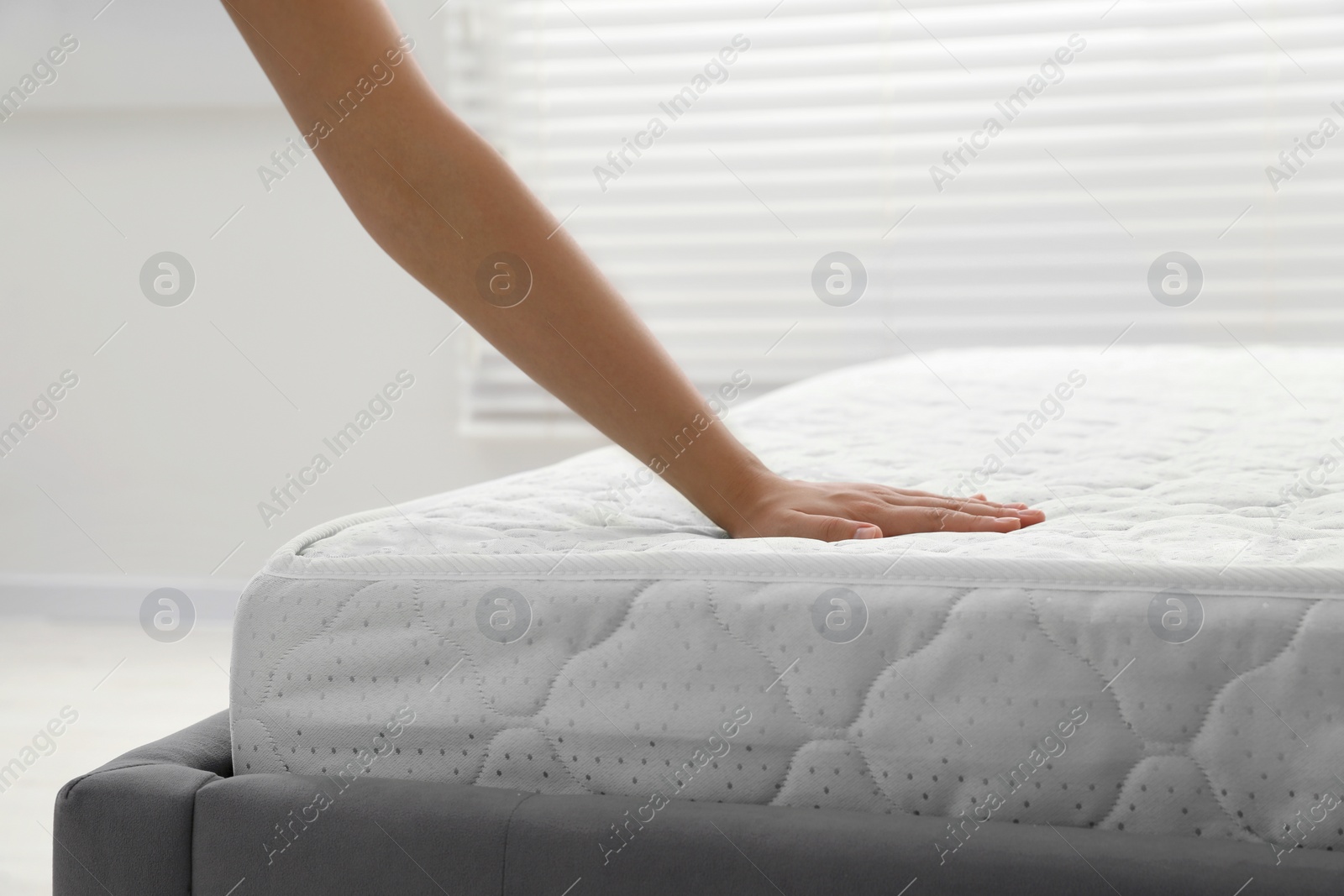 Photo of Woman touching soft light green mattress indoors, closeup