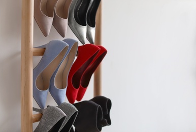 Photo of Rack with high heeled shoes on light background