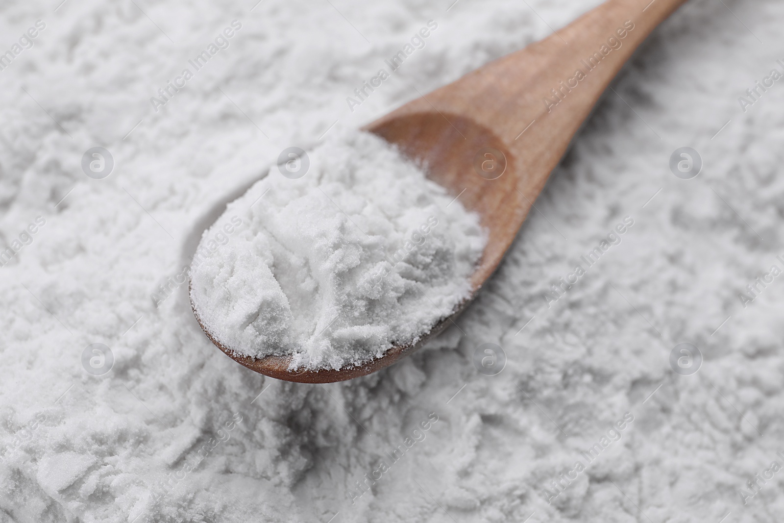 Photo of Heap of natural starch and wooden spoon, closeup