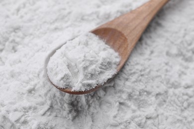 Photo of Heap of natural starch and wooden spoon, closeup