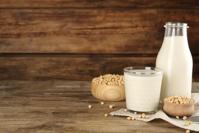 Photo of Fresh soy milk and grains on wooden table. Space for text