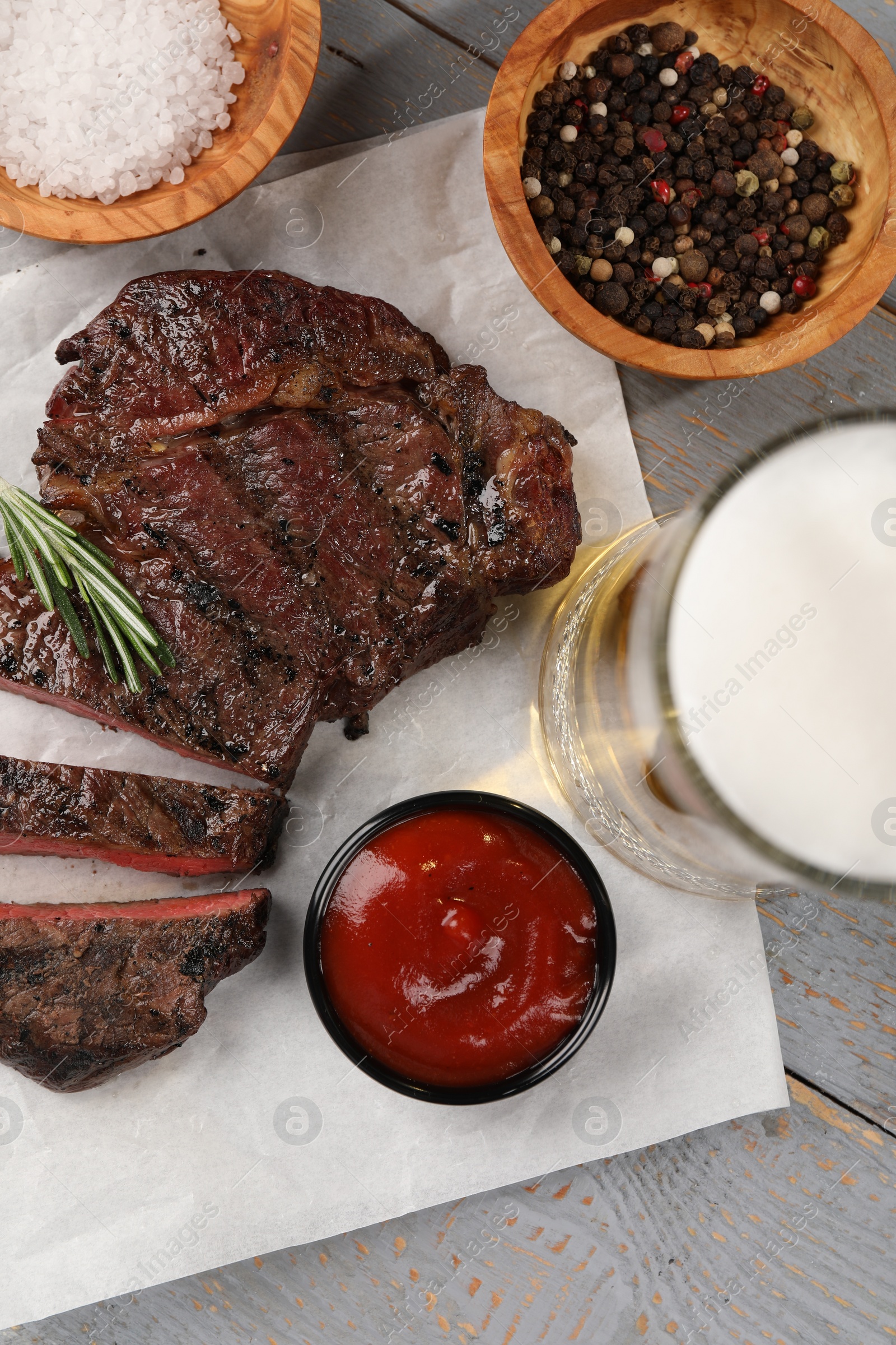 Photo of Mug with beer, fried steak and sauce on grey wooden table, flat lay