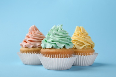 Photo of Tasty cupcakes with cream on light blue background