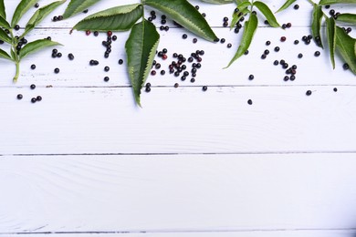 Photo of Tasty elderberries (Sambucus) on white wooden table, flat lay. Space for text