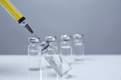 Photo of Filling syringe with medicine from vial on white table
