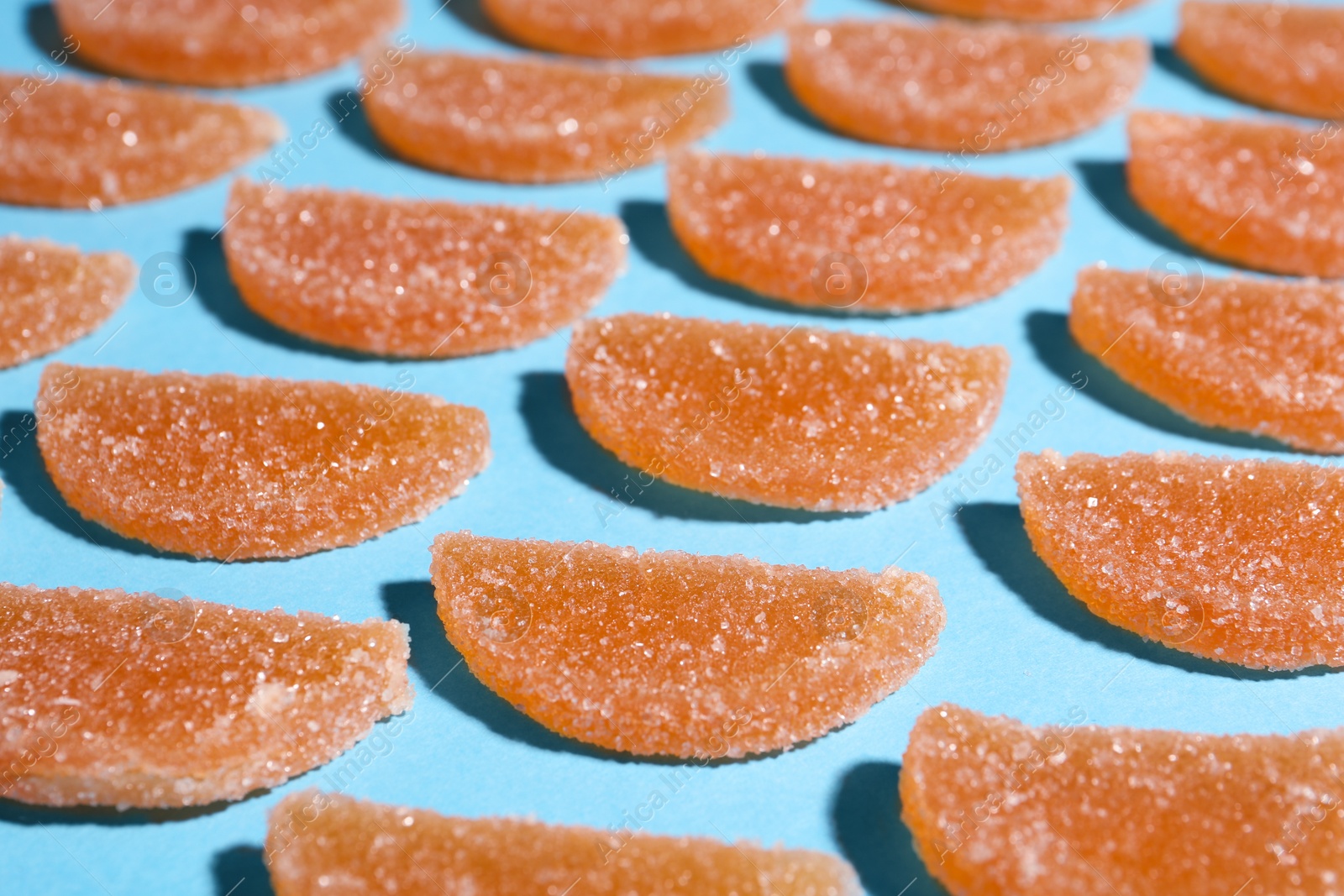Photo of Delicious orange marmalade candies on light blue background