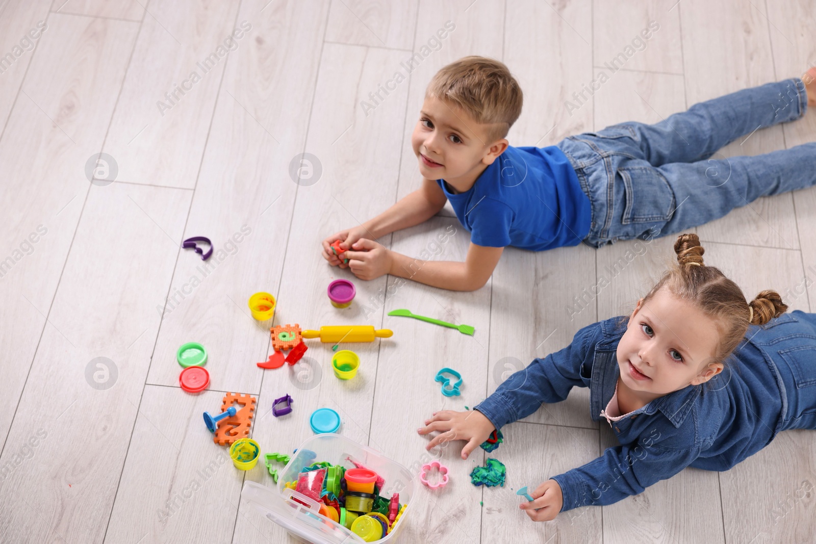 Photo of Cute little children playing on warm floor indoors, space for text. Heating system