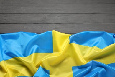 Photo of Flag of Sweden on gray wooden background, top view. Space for text