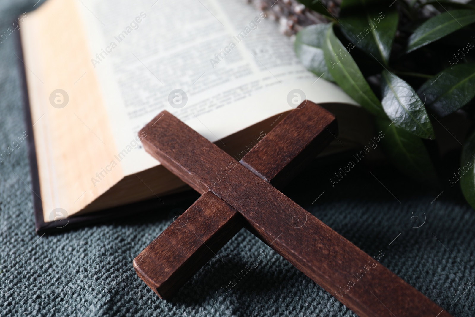 Photo of Wooden cross and Bible on table, closeup