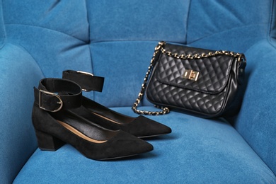 Photo of Pair of female shoes and bag on armchair