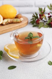 Glass cup of delicious immunity boosting tea with ingredients on light grey table