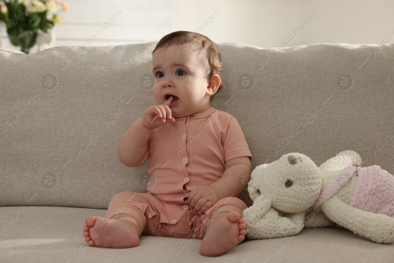 Photo of Cute little baby with bunny toy on sofa at home