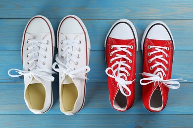 Photo of Different stylish sneakers on light blue wooden table, flat lay