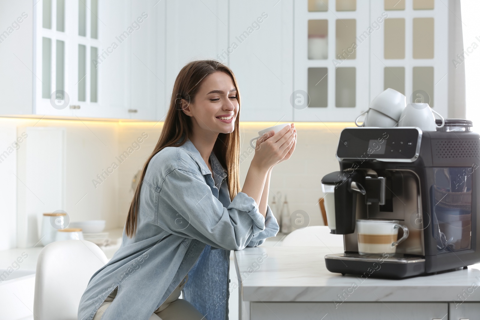 Photo of Young woman enjoying fresh aromatic coffee near modern machine in kitchen