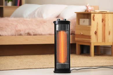 Photo of Modern infrared heater on floor in cozy room