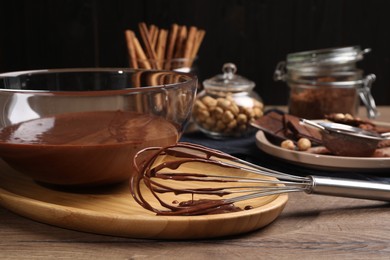 Photo of Bowl and whisk with chocolate cream on wooden table