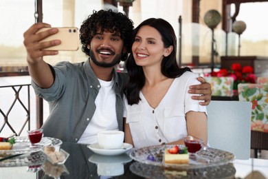 Photo of International dating. Happy couple taking selfie in restaurant