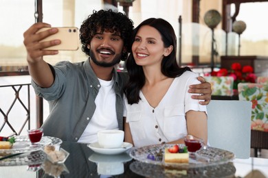 International dating. Happy couple taking selfie in restaurant