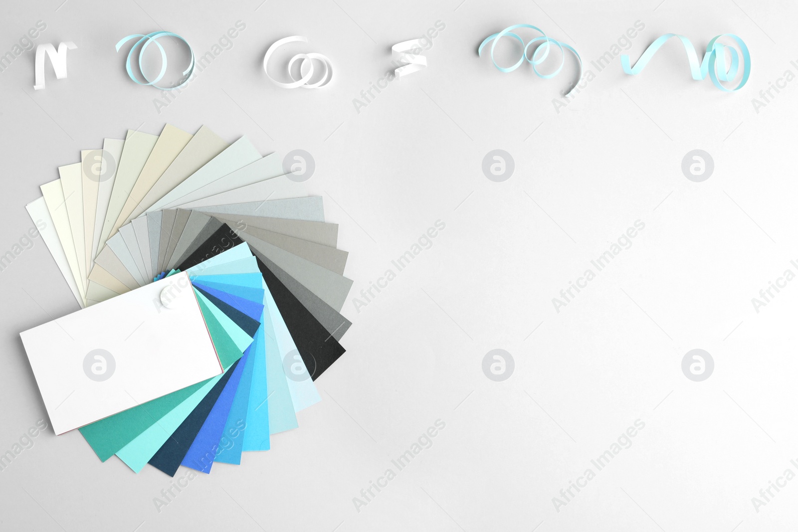 Photo of Color palette and paper curls on white background, flat lay