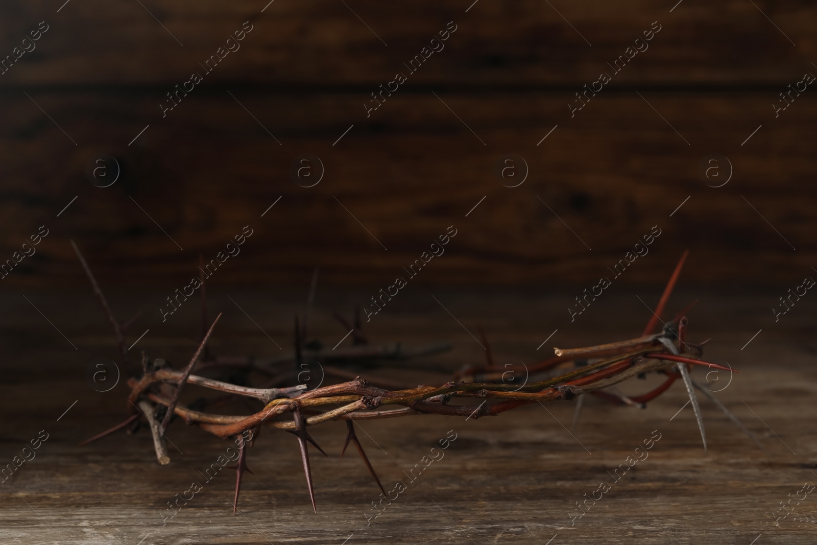 Photo of Crown of thorns on wooden table, space for text. Easter attribute