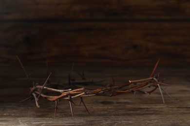 Photo of Crown of thorns on wooden table, space for text. Easter attribute