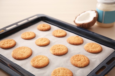 Baking tray with cookies and coconut on table, closeup