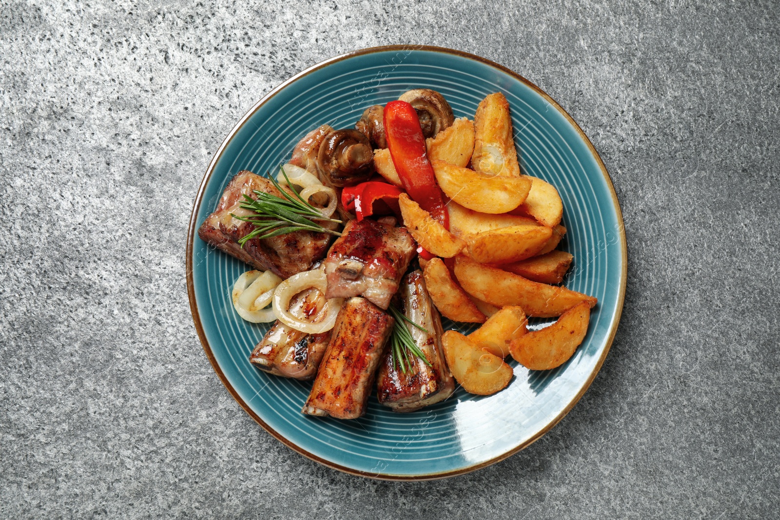 Photo of Delicious grilled ribs and garnish on grey table, top view