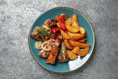 Delicious grilled ribs and garnish on grey table, top view