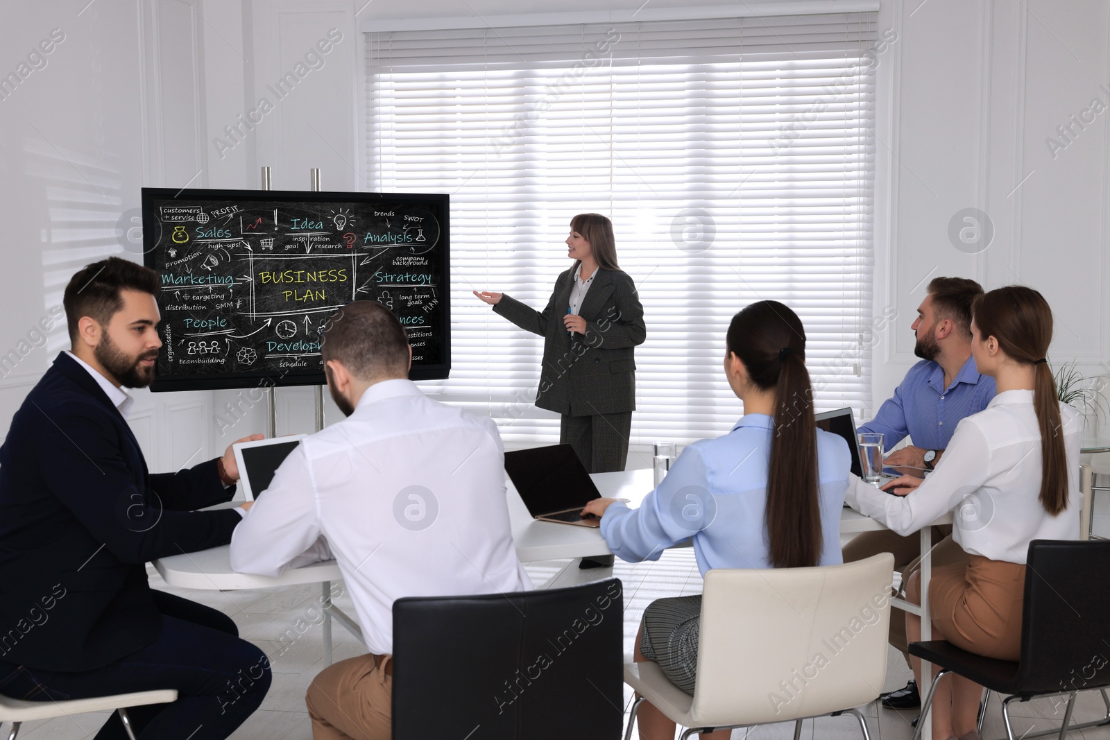 Photo of Business trainer using interactive board in meeting room during presentation