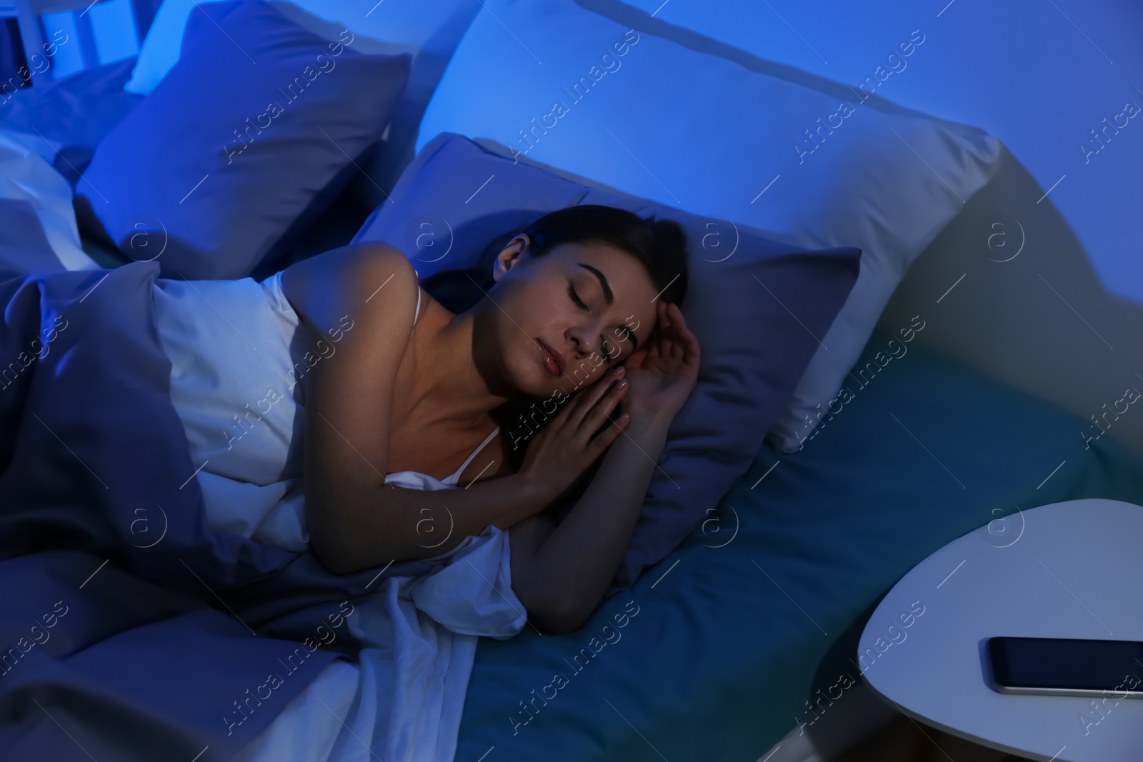 Photo of Young woman sleeping on soft pillow at night. Bedtime
