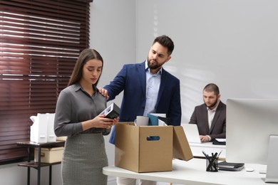 Photo of Colleague comforting dismissed young woman in office