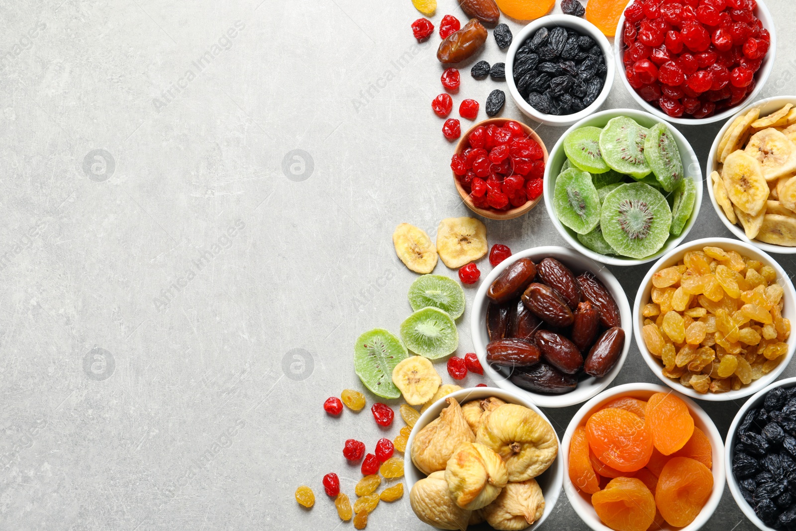 Photo of Bowls of different dried fruits on grey background, top view with space for text. Healthy food