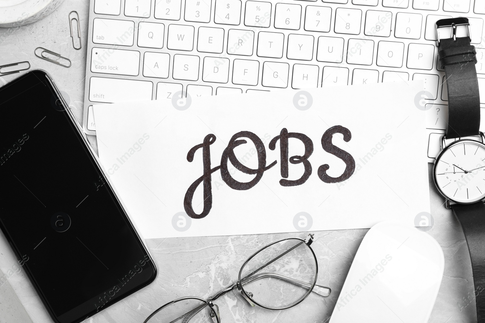 Photo of Flat lay composition with word JOBS, computer keyboard and smartphone on light grey marble table. Career concept