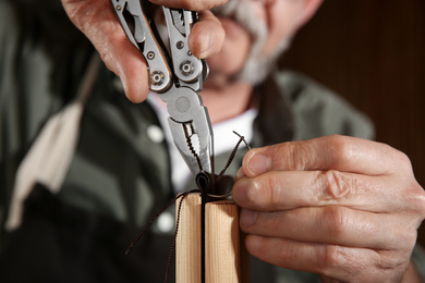 Man sewing piece of leather in workshop, closeup