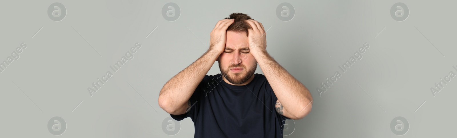 Image of Tired man suffering from migraine on grey background. Banner design