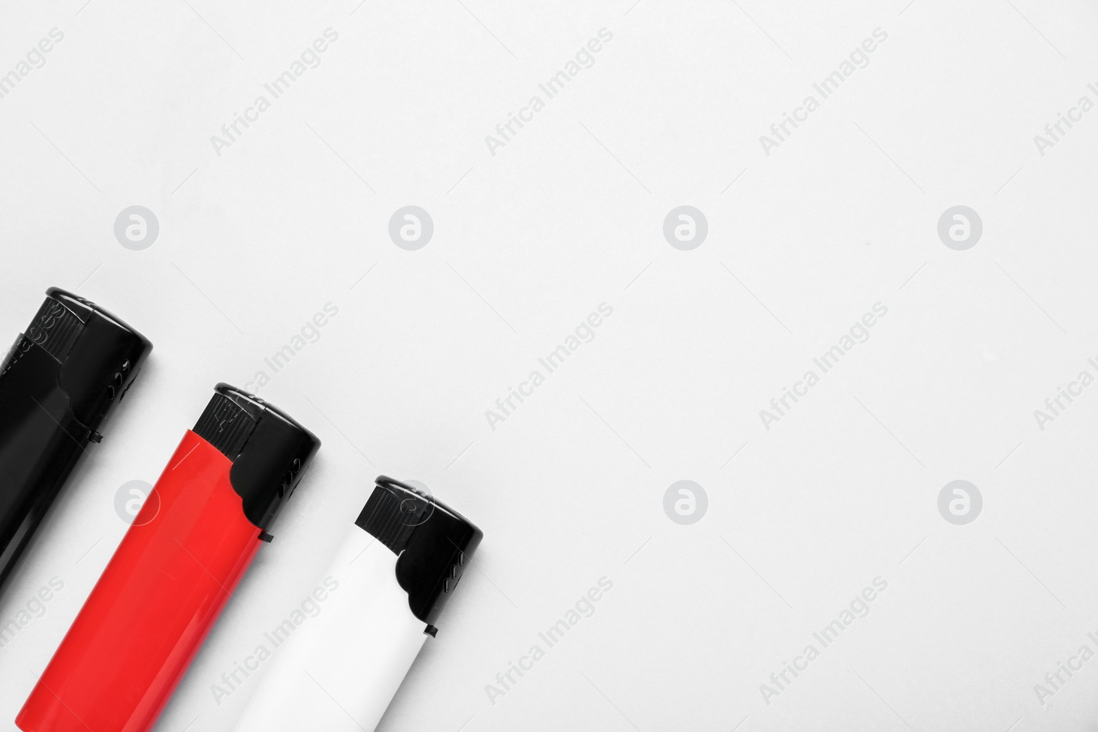 Photo of Stylish small pocket lighters on white background, flat lay. Space for text