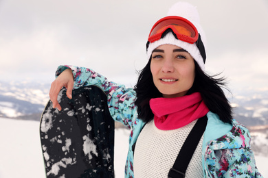 Beautiful young woman with snowboard on snowy hill. Winter vacation