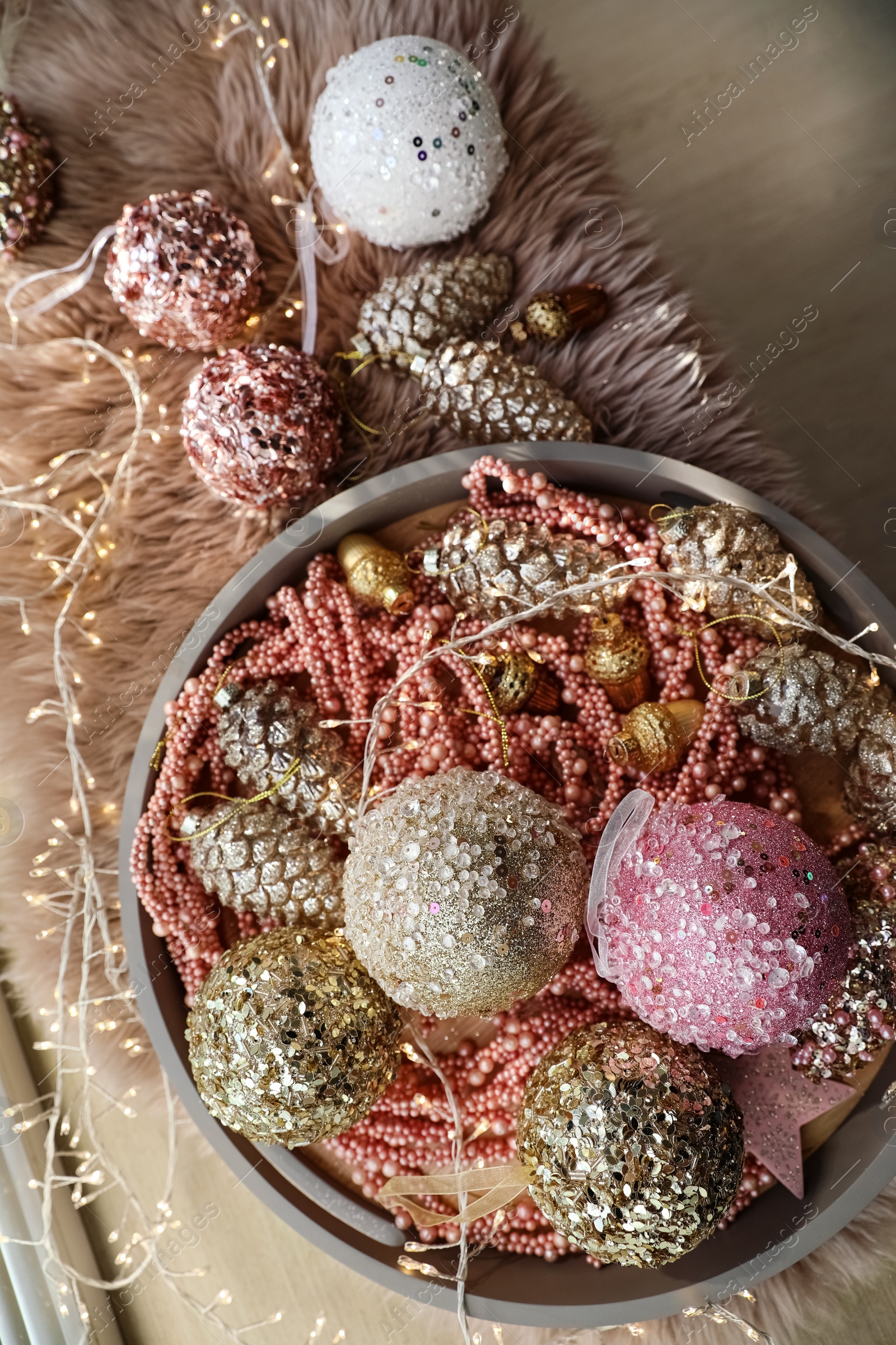 Photo of Beautiful Christmas tree baubles and fairy lights on faux fur, flat lay