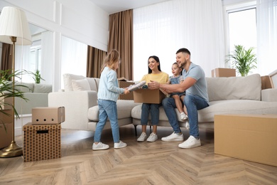 Happy family unpacking moving box at their new house