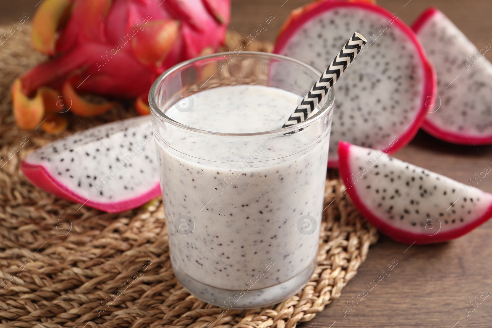 Photo of Delicious pitahaya smoothie and fresh fruits on wooden table, closeup