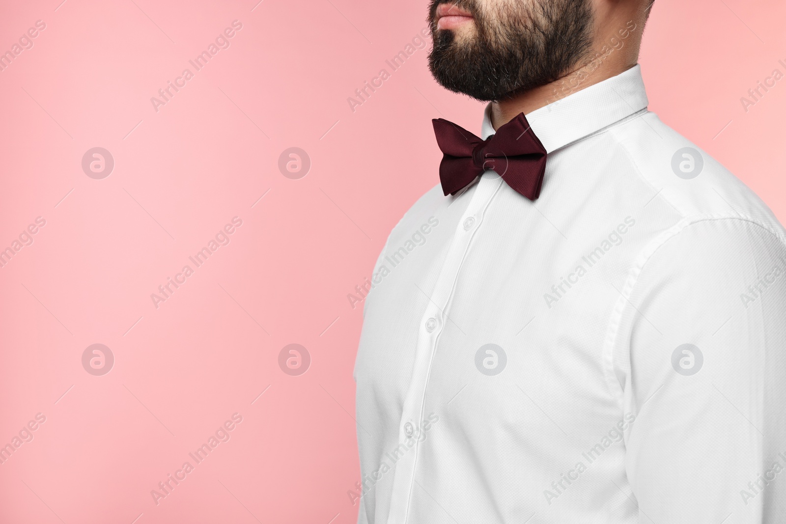 Photo of Man in shirt and bow tie on pink background, closeup. Space for text