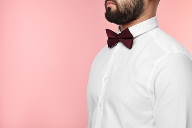 Photo of Man in shirt and bow tie on pink background, closeup. Space for text