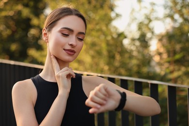 Photo of Attractive happy woman checking pulse after training in park