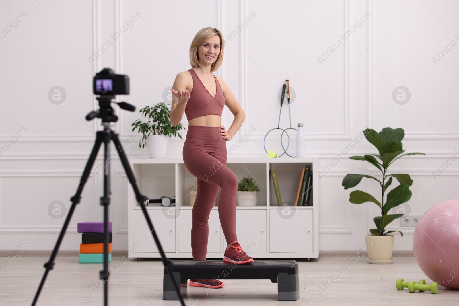 Photo of Smiling sports blogger recording fitness lesson with camera at home