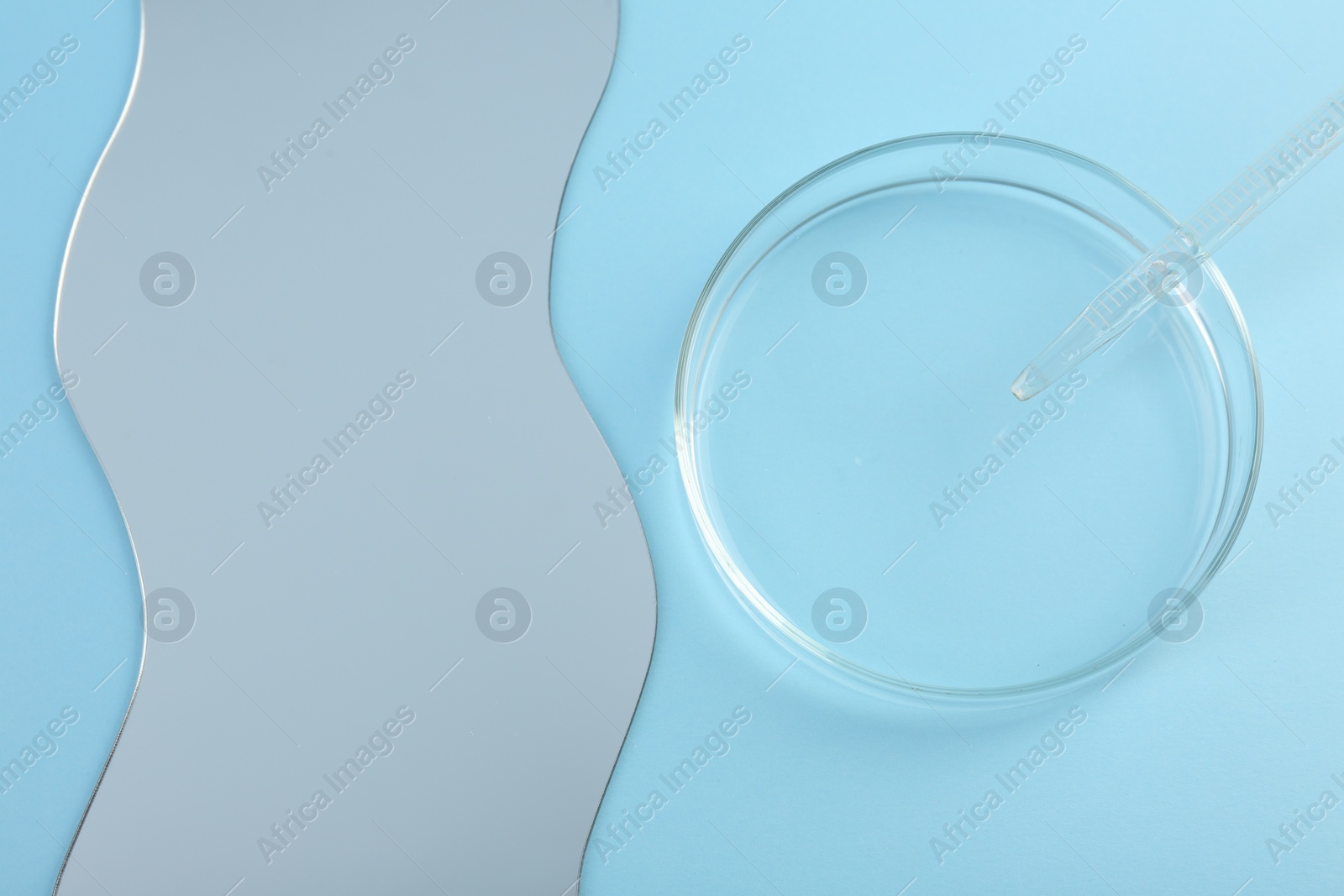 Photo of Empty petri dish, pipette and mirror on light blue background, flat lay