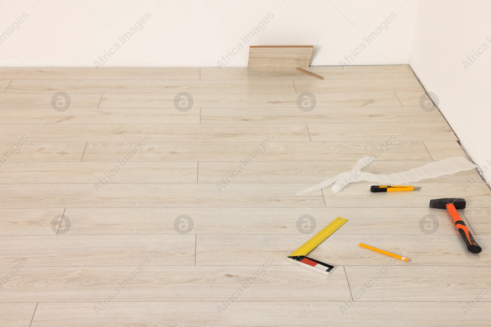 Photo of Hammer, cutter knife, pencil and ruler on laminated floor. Space for text