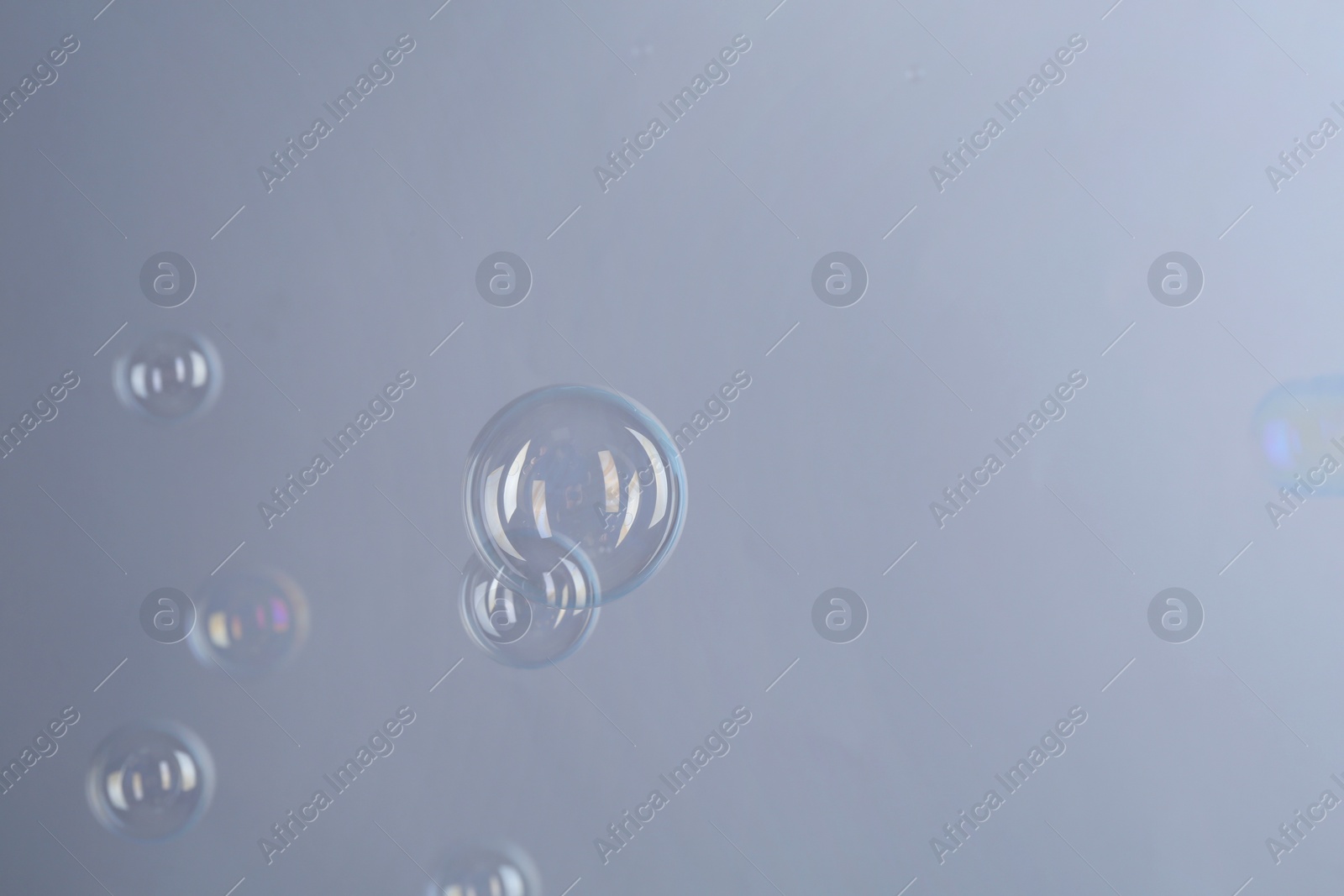 Photo of Beautiful transparent soap bubbles on gray background, space for text