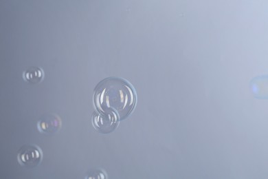 Beautiful transparent soap bubbles on gray background, space for text