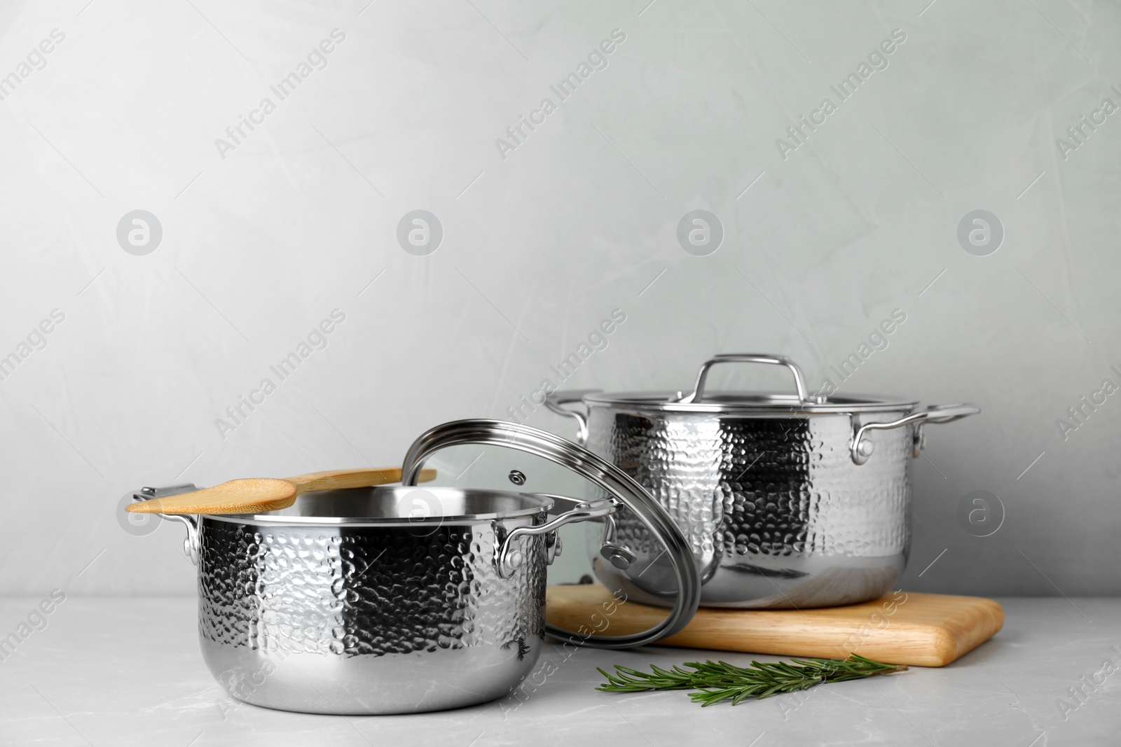 Photo of New clean saucepans on table against grey background, space for text