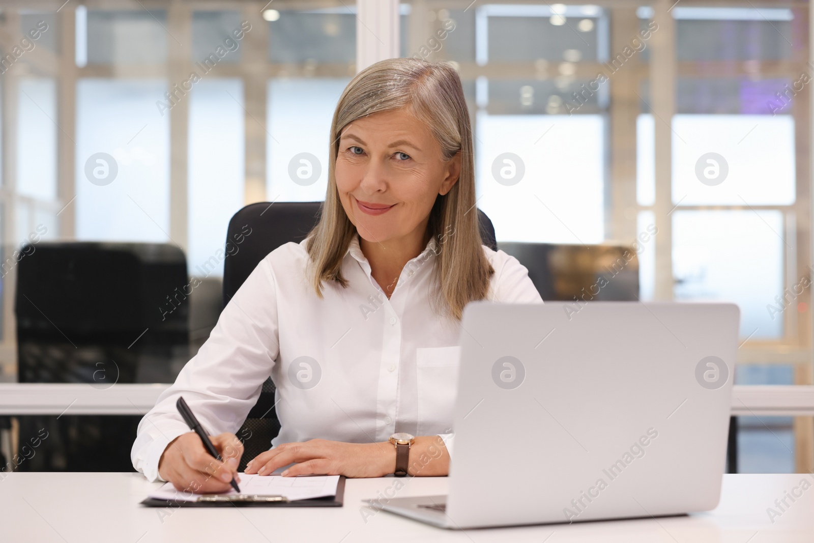 Photo of Confident woman with clipboard and laptop working in office. Lawyer, businesswoman, accountant or manager